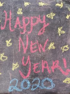Another decade gone! Picture shows 'happy New Year 2020' in red chalk on the sidewalk with yellow stars