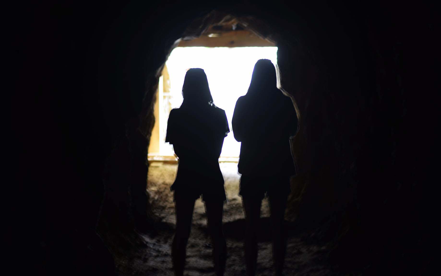 Though Ashley is still in NZ's newest lockdown, there is light at the end of the tunnel. Picture of two silhouetted figures in a tunnel with light streaming in behind them.