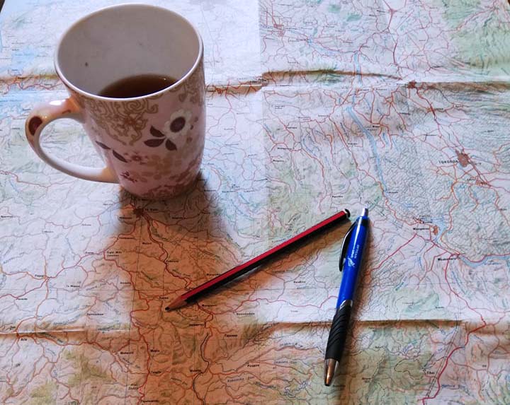 The outline becomes our road map for the novel. Picture of a road map, a pen and pencil, and a mug of tea resting on top